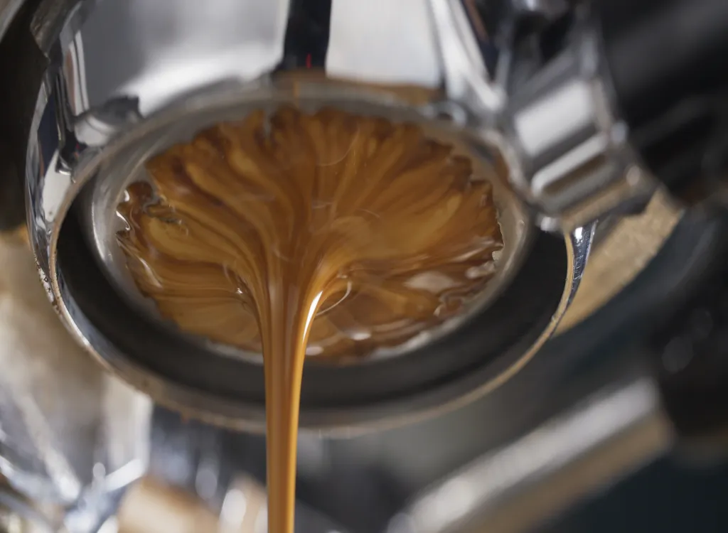 A closeup of espresso coffee extraction on a touch espresso machine.