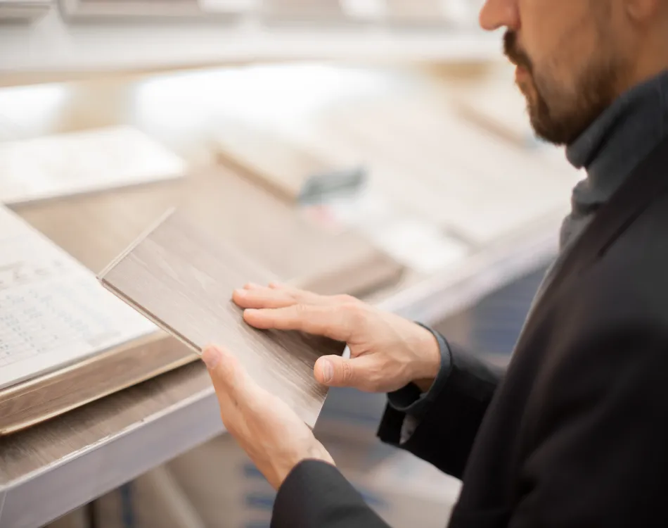 A man examining a piece of laminate flooring.
