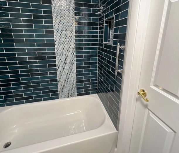 A tub-shower combo with blue tiles and mosaic accent