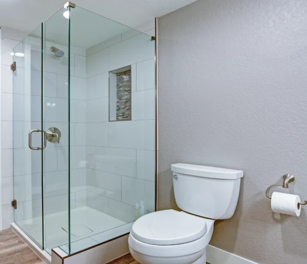 Corner shower with large white tiles and glass door
