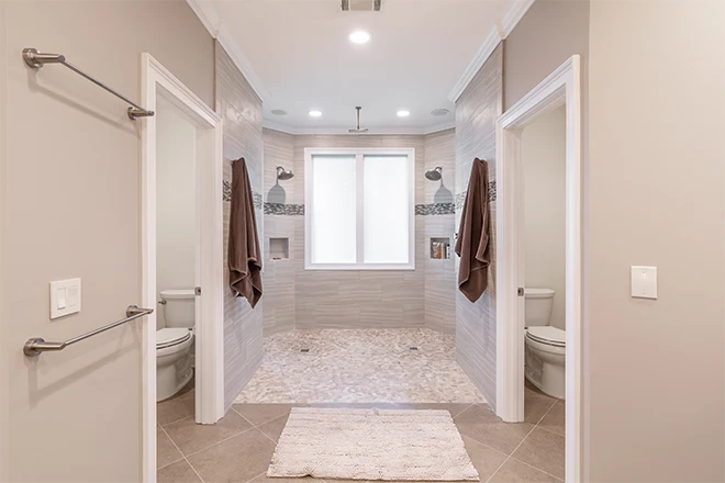 Open concept wet room bathroom with dual shower and separate toilet rooms