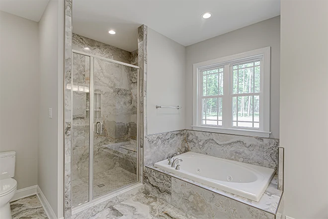 Built in bathtub with separate shower both with white marble surround