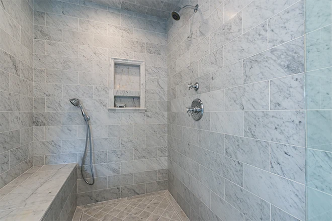 Luxury walk in shower with gray and white marble walls bench and flooring with chrome finishes