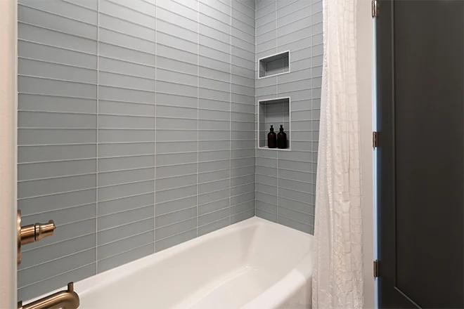 Sleek bathroom tub with blue gray tile and gold faucets